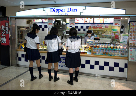 Three high school girls in uniform purchasing an after-school snack in an underground mall in Nagoya, Japan.