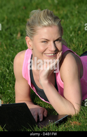 Woman using her notebook computer on the grass Stock Photo
