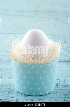 White easter egg in a blue cupcake cup on wooden vintage background Stock Photo