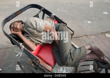 A rickshaw puller takes a quick nap on his rickshaw In Delhi, India Stock Photo