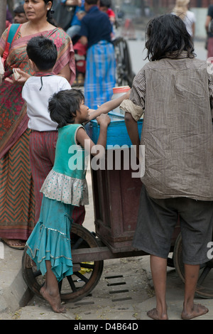 A child beggar buys sweets from a street vendor In Kolkata, India Stock Photo