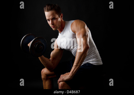 Attractive male doing dumbbell lifts and flexing arm Stock Photo