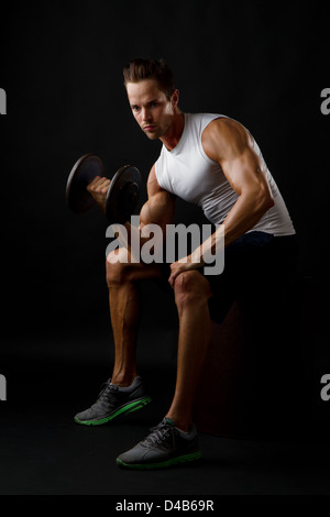 Attractive male doing dumbbell lifts and flexing arm Stock Photo