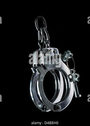 Steel police handcuffs with unlocking keys shot on black background