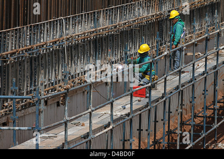 Two employees working on scaffolding and welding metal support rods Stock Photo