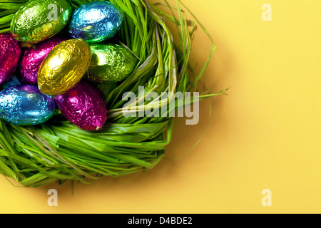 Colorful easter eggs in green nest. Holiday chocolate background. Top view. Macro shot Stock Photo