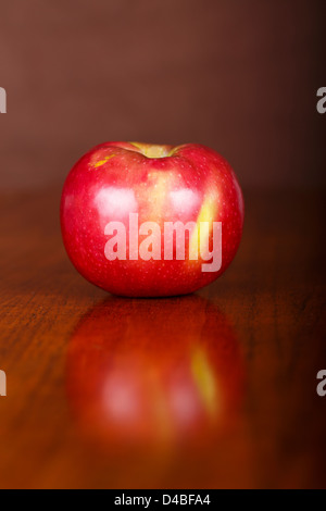 A single macintosh apple on a wood table with slight reflection Stock Photo