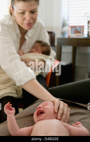 A single mom comforting her 7 week old infant twins Stock Photo