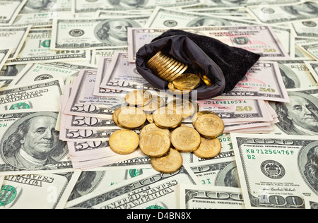 Bag filled with coins over US banknotes background Stock Photo