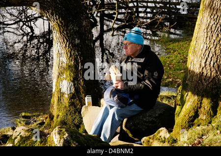 An older man eating a sandwich on a winter picnic break in the Lake District Stock Photo
