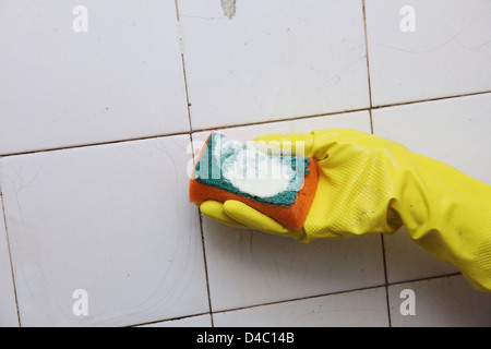gloved hand cleaning dirty old tiles with brush in a bathroom Stock ...