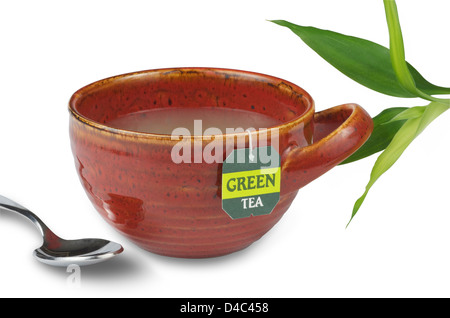 Cup of green tea in a red modern tea cup with spoon and green bamboo sprig. Stock Photo