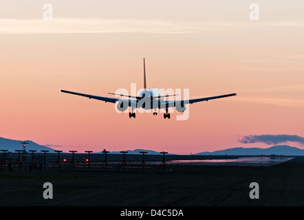 Silhouetted passenger jet airliner landing at sunset dusk with colorful sky Vancouver International Airport Stock Photo