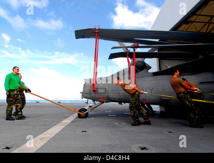 Members from Helicopter Sea Combat Squadron 23 “Wild Cards” Pull an MH-60S Knighthawk Helicopter Across the Flight Deck Stock Photo