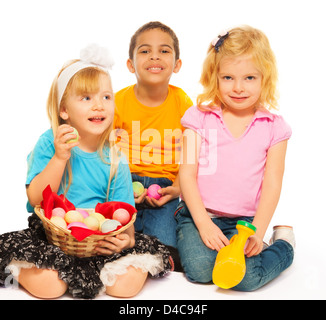 Three kids with Easter eggs - two blond girls and black boy Stock Photo