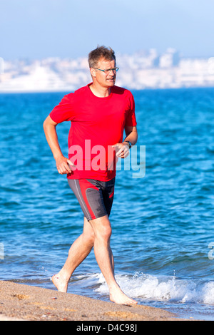 Happy young man running on the beach Stock Photo