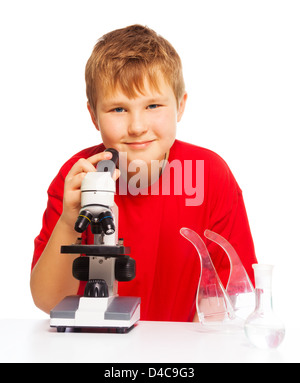 Fat happy Caucasian boy with short hair in chemistry lab class with microscope and test tubes on the table, isolated on white Stock Photo