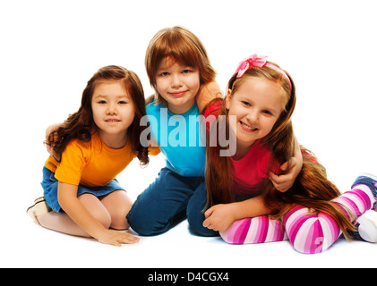 Group of three kids, two girls and boy together, Asian and Caucasian happy, hugging, sitting isolated on white Stock Photo