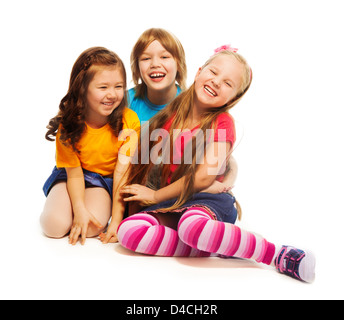 Group of three kids, two girls and boy together, diversity looking happy, laughing, hugging, sitting isolated on white Stock Photo