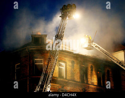 Firemen use turntable ladders to fight a fire at a multi-family house in Ludwigshafen, Germany, 03 February 2008. Over 60 people were injured in the incident, including children and police officials who meant to rescue inhabitants. The fire's source is yet undetermined, as the area is still largely cordoned off. Photo: BORIS ROESSLER Stock Photo