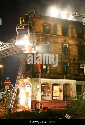 Firemen use turntable ladders to fight a fire at a multi-family house in Ludwigshafen, Germany, 03 February 2008. Over 60 people were injured in the incident, including children and police officials who came to rescue inhabitants. The fire's source is yet undetermined, as the area is still largely cordoned off. Photo: BORIS ROESSLER Stock Photo