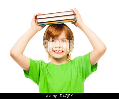 Happy Caucasian 9 years old boy in green shirt holding stack of books on top of head portrait, close-up portrait, isolated on white Stock Photo