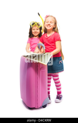 Two cute little exited girls standing with suitcase with map preparing to travel deciding destinations, wearing snorkel and mask, isolated on white Stock Photo