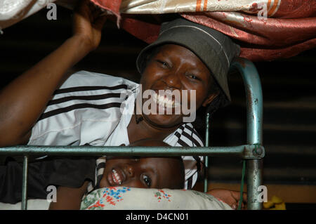 The picture shows a man and a child smiling on a bed inside a hut in the Huruma slum in Nairobi, Kenya, 28 November 2007. Photo: Sandra Gaetke Stock Photo