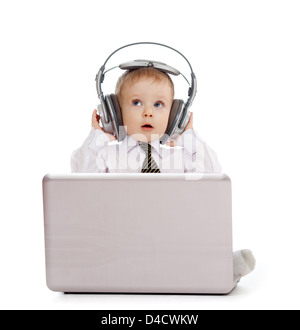 Funny child playing with laptop and listening to music in headphones Stock Photo