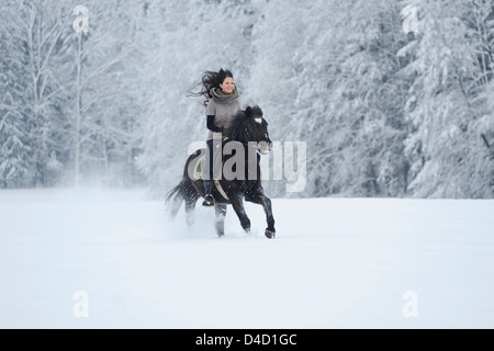 Young woman riding on horse in snow Stock Photo