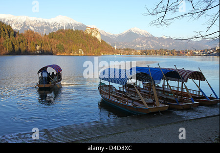 A Pletna a covered wooden rowing boat  with snow capped mountains on Lake Bled Slovenia Europe Stock Photo