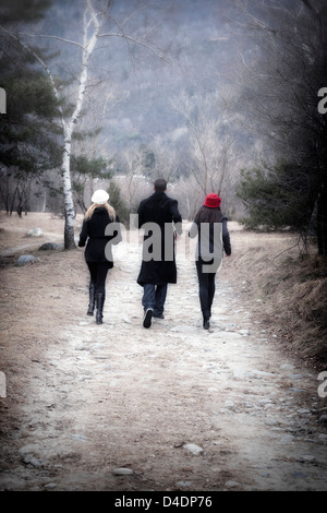 one man and two women running through a forest Stock Photo