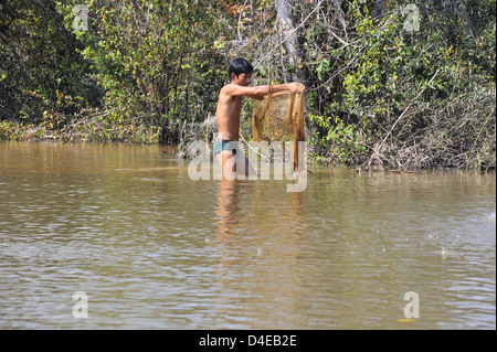 Young man using a throw net to catch fish in rural Cambodia Stock