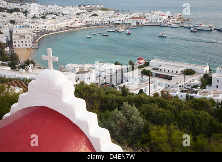 Red domed church with white cross overlooking Mykonos harbour and town of Chora in the Greek islands Stock Photo