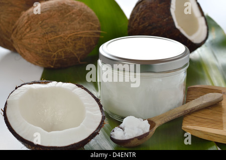 Coconuts and organic coconut oil in a glass jar on white background. Hair treatment. Stock Photo