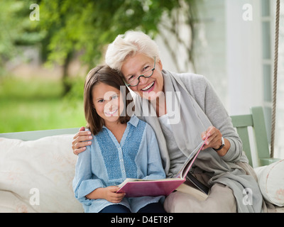 Woman and granddaughter smiling in porch swing Stock Photo