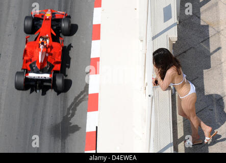 A woman wearing a bikini watches Formula One driver Kimi Raikkonen of Ferrari as he steers his car on the track during the first practice session for the F1 Grand Prix in Monte Carlo, Monaco, 22 May 2008. The Formula One Grand Prix of Monaco will take place on 25 May. Photo: Gero Breloer Stock Photo