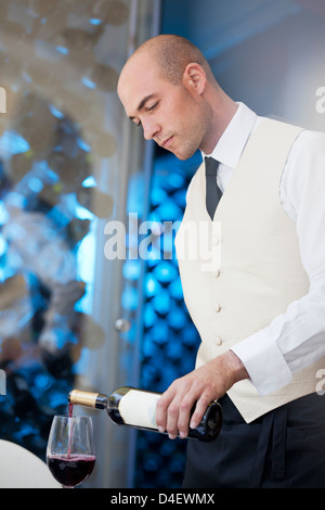 Waiter pouring glass of wine in restaurant Stock Photo