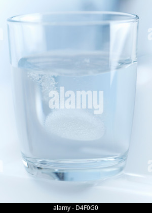 Close up of pill fizzing in glass of water Stock Photo