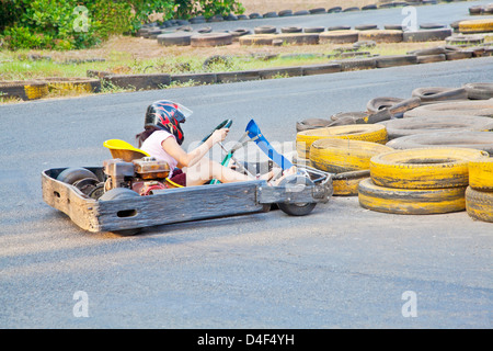 young lady at the wheel of a go-kart who lost control at a left hand turn and crashed into the tire barriers race track Stock Photo