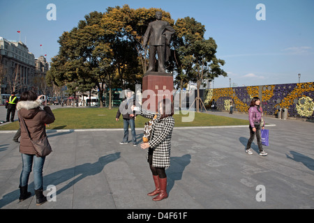 Tourists taking photographs by a statue in the The Bund, Shanghai, China Stock Photo