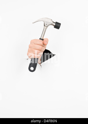 close-up of male hand holding a hammer through a torn white paper, isolated Stock Photo