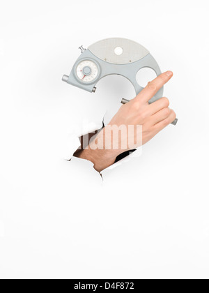 close-up of male hand holding a micrometer through a torn white paper, isolated Stock Photo
