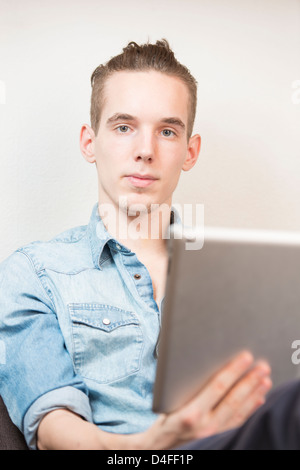 Lifestyle moment with a relaxed young adult male holding a digital tablet device in his hands. Stock Photo