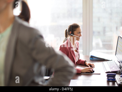 Businesswoman wearing headset at desk Stock Photo