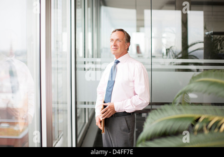 Businessman standing at office window Stock Photo