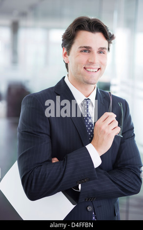 Businessman smiling in office hallway Stock Photo