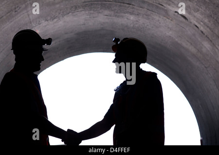 Silhouette of workers shaking hands in tunnel Stock Photo