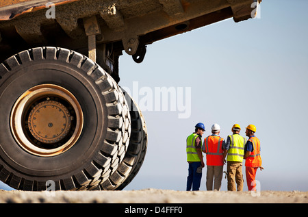 Workers talking by machinery on site Stock Photo