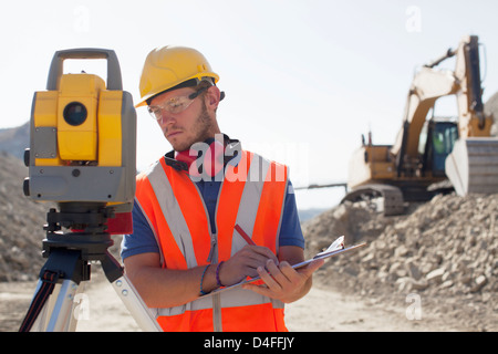 Worker using leveling equipment in quarry Stock Photo